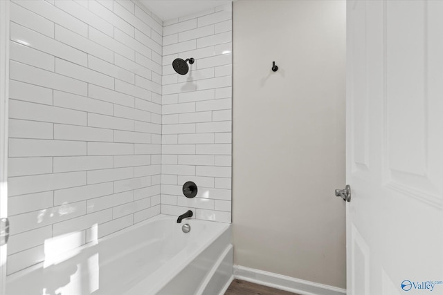 bathroom featuring bathtub / shower combination, baseboards, and wood finished floors