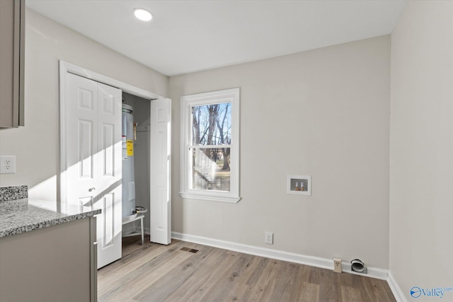 interior space featuring hookup for a washing machine, laundry area, baseboards, and light wood-style floors