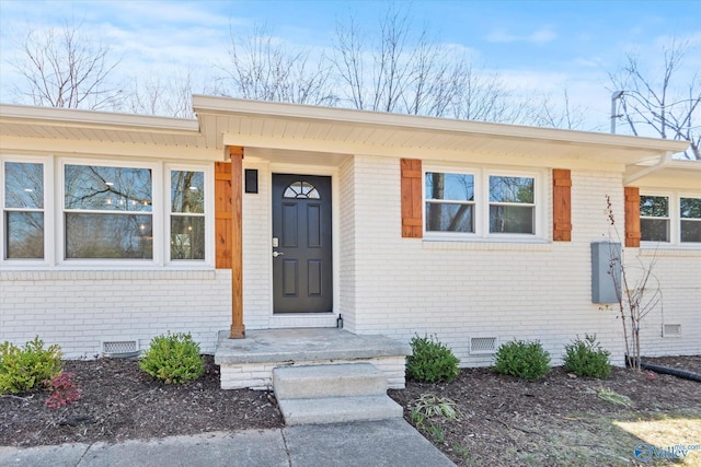 view of exterior entry featuring brick siding and crawl space