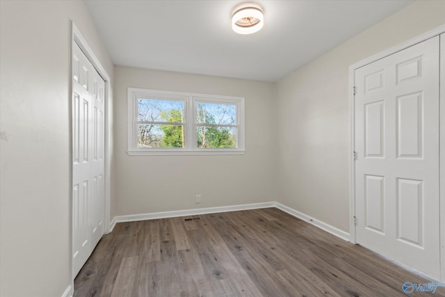 unfurnished bedroom with a closet, baseboards, and wood finished floors