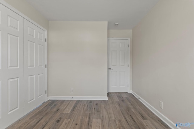 unfurnished bedroom with a closet, wood finished floors, and baseboards