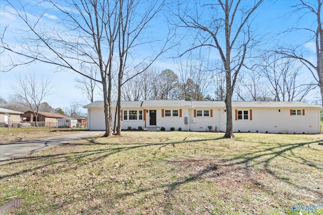 ranch-style house featuring a front yard, fence, driveway, and an attached garage