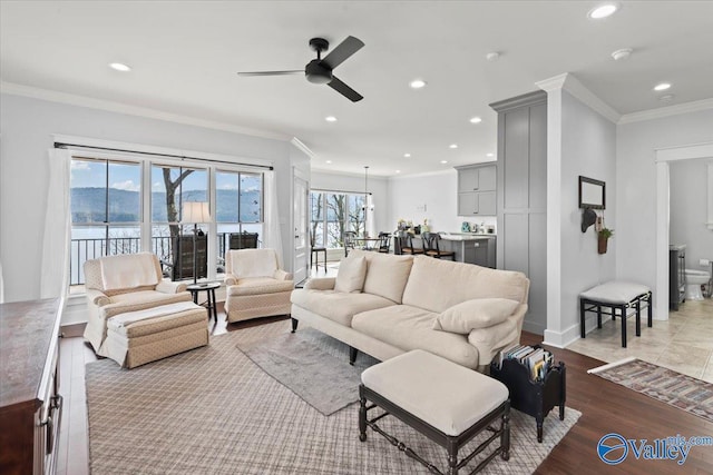 living room featuring crown molding, a wealth of natural light, ceiling fan, and light hardwood / wood-style flooring