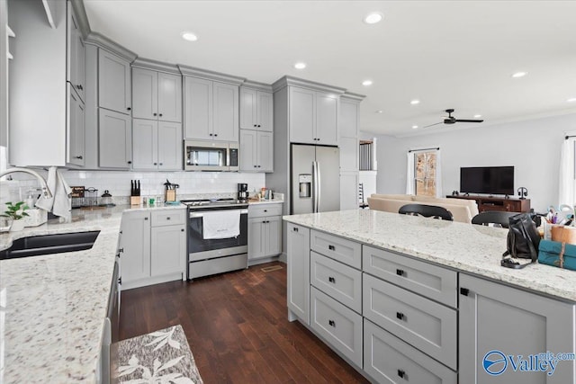 kitchen with sink, tasteful backsplash, appliances with stainless steel finishes, gray cabinets, and light stone countertops