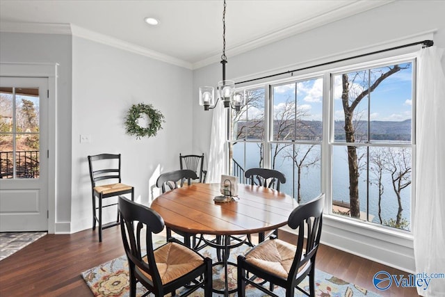 dining space featuring dark hardwood / wood-style flooring, crown molding, an inviting chandelier, and a water view