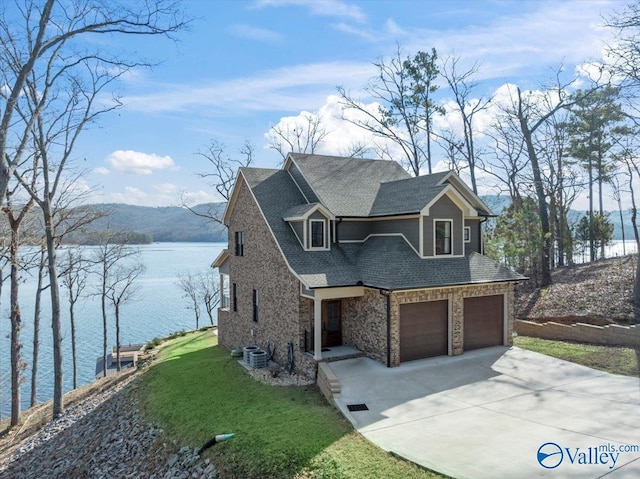 view of front of house featuring cooling unit, a garage, a water and mountain view, and a front lawn