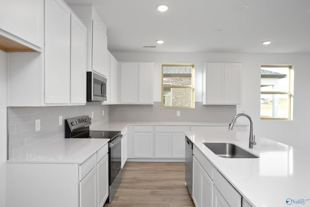 kitchen with sink, plenty of natural light, stainless steel appliances, and white cabinets