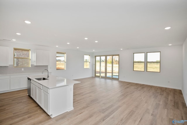 kitchen with a kitchen island with sink, sink, white cabinets, and light hardwood / wood-style floors