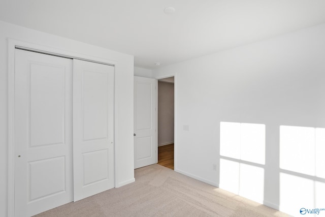 unfurnished bedroom with light colored carpet and a closet