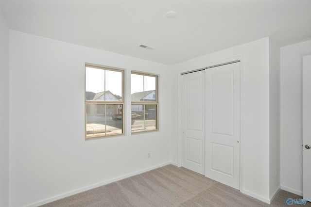 unfurnished bedroom featuring light colored carpet and a closet