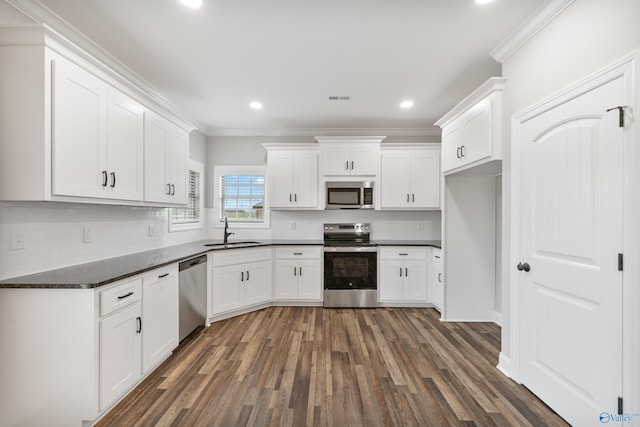 kitchen with ornamental molding, visible vents, appliances with stainless steel finishes, a sink, and wood finished floors