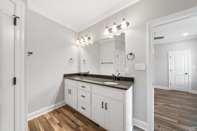 bathroom with a sink, baseboards, wood finished floors, and crown molding