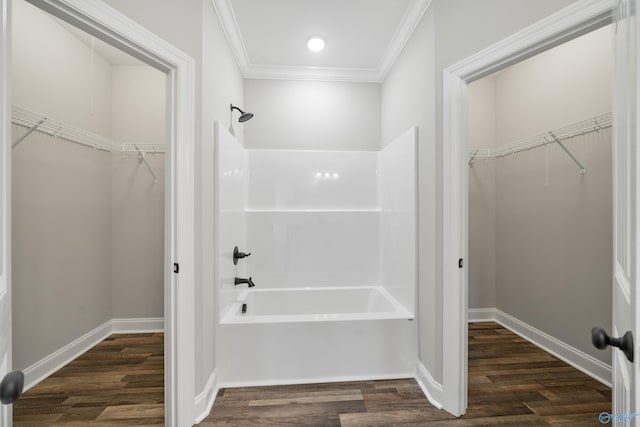 bathroom featuring crown molding, bathtub / shower combination, wood finished floors, a walk in closet, and baseboards