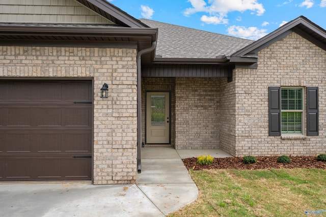 property entrance featuring brick siding, an attached garage, and roof with shingles