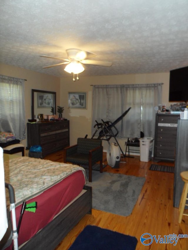 bedroom with wood-type flooring, a textured ceiling, and ceiling fan