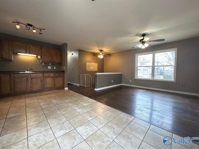 unfurnished living room with sink, ceiling fan, and light tile patterned flooring