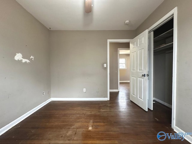 unfurnished bedroom with dark hardwood / wood-style flooring, a closet, and ceiling fan