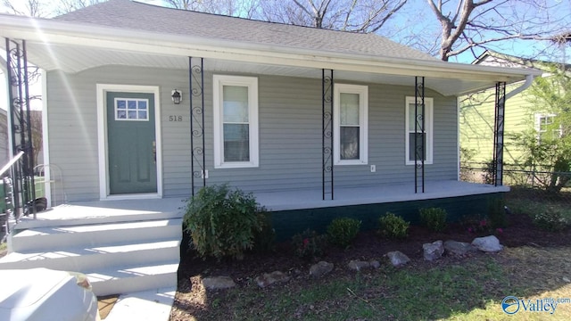 view of front of home with a porch, roof with shingles, and fence