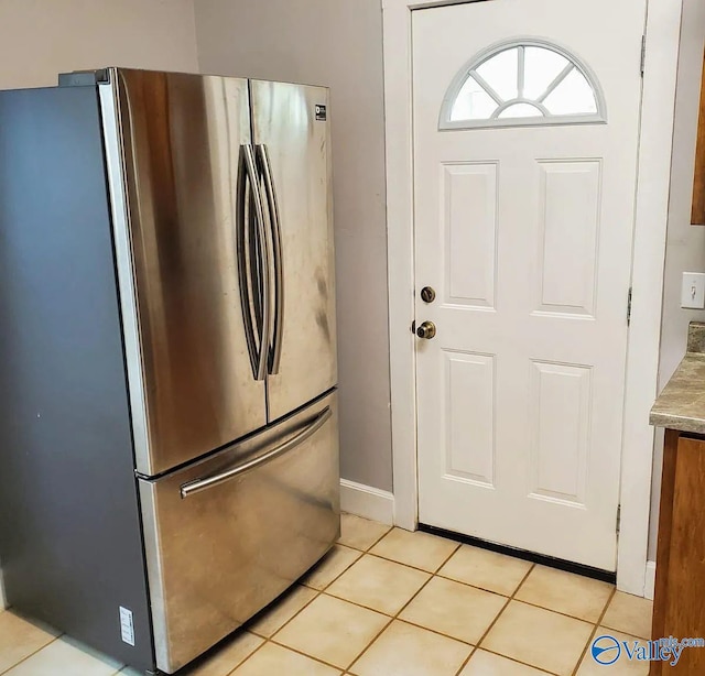 kitchen with freestanding refrigerator, light tile patterned flooring, baseboards, and light countertops