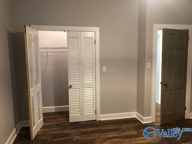 interior space featuring a closet, baseboards, and dark wood finished floors