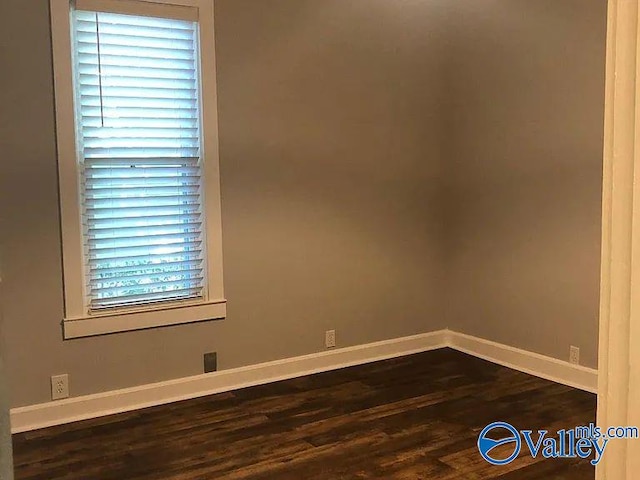 empty room featuring baseboards and dark wood-type flooring