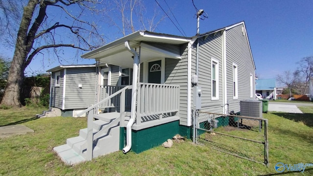 bungalow featuring central AC unit, a front lawn, and fence