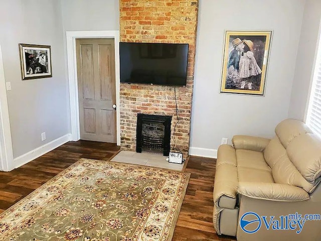 living area with a brick fireplace, baseboards, and wood finished floors