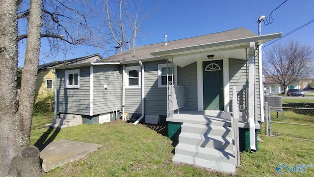 view of front of property with fence, central AC unit, a shingled roof, and a front yard