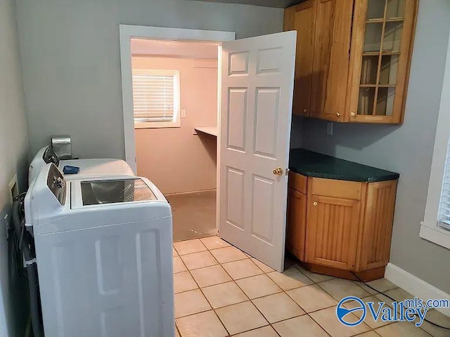 laundry area featuring light tile patterned floors, cabinet space, and washer and clothes dryer