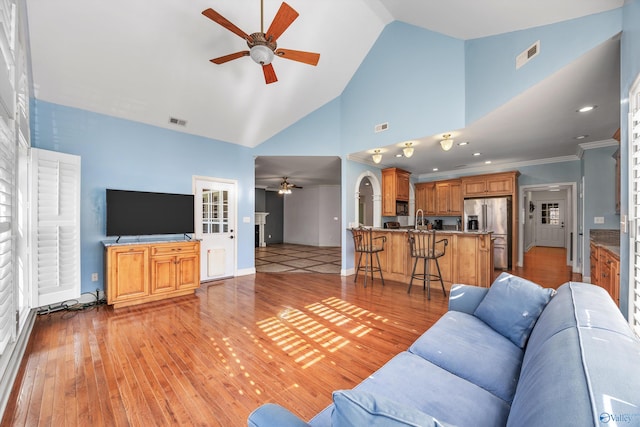 living room featuring ceiling fan, high vaulted ceiling, light hardwood / wood-style floors, and ornamental molding