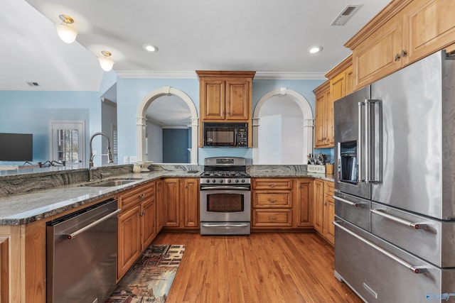 kitchen with sink, stainless steel appliances, kitchen peninsula, light hardwood / wood-style floors, and ornamental molding