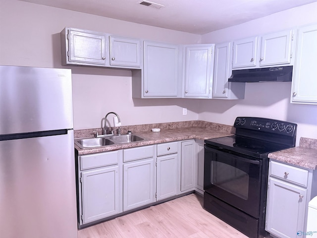 kitchen with white cabinetry, sink, stainless steel fridge, and black range with electric cooktop