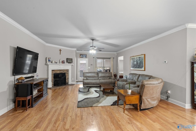 living area with ceiling fan, baseboards, a stone fireplace, and light wood finished floors
