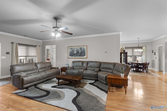 living area with ceiling fan with notable chandelier, light wood-style floors, and crown molding