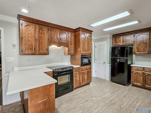 kitchen featuring light hardwood / wood-style flooring, black appliances, a textured ceiling, and crown molding