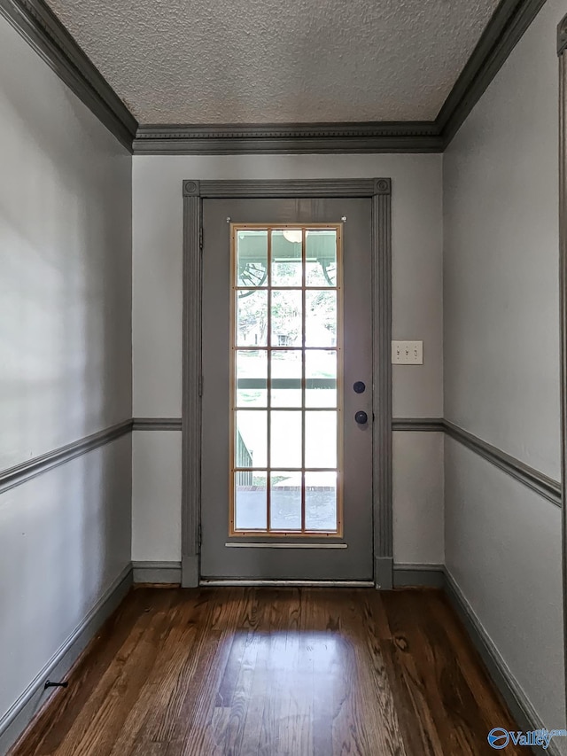 doorway to outside featuring a textured ceiling, crown molding, and dark hardwood / wood-style floors