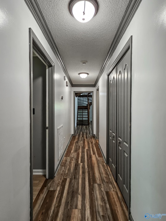 hallway with a textured ceiling, ornamental molding, and dark hardwood / wood-style floors