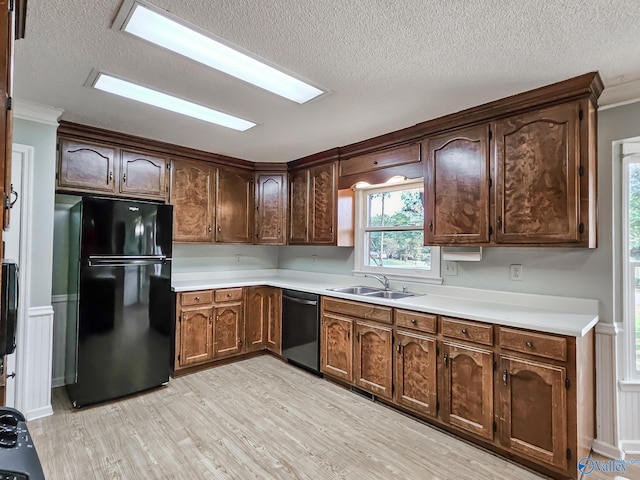 kitchen with a textured ceiling, sink, light hardwood / wood-style flooring, black appliances, and crown molding