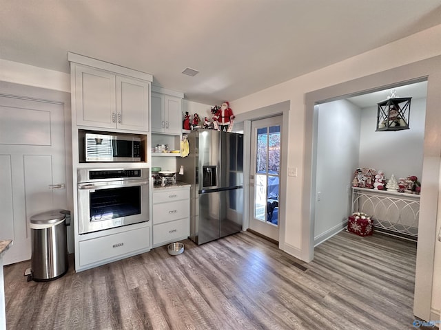 kitchen with white cabinets, light wood-type flooring, and appliances with stainless steel finishes