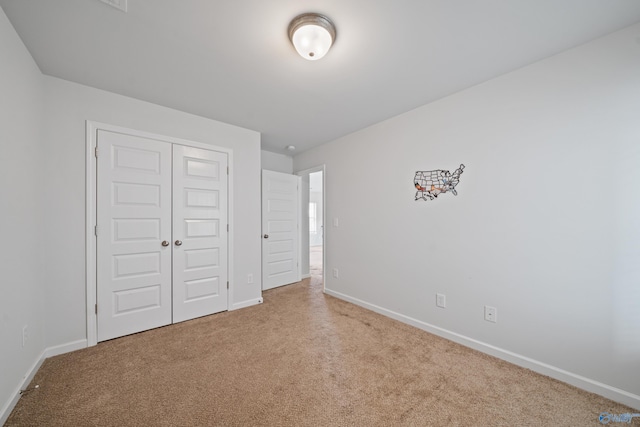 unfurnished bedroom featuring light carpet and a closet