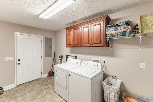 laundry room with a textured ceiling, electric panel, baseboards, washer and clothes dryer, and cabinet space