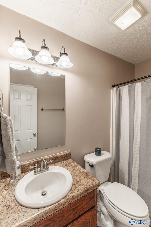 bathroom with a shower with curtain, toilet, a textured ceiling, and vanity