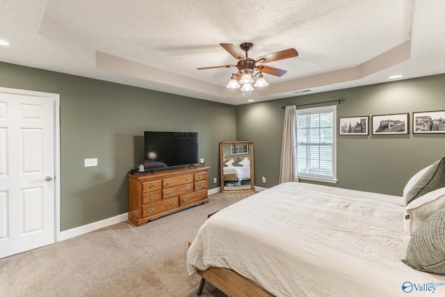 bedroom with recessed lighting, a tray ceiling, light carpet, baseboards, and a textured ceiling
