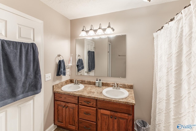 full bath featuring double vanity, a sink, and a textured ceiling