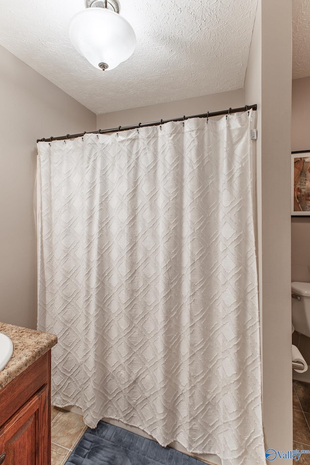 full bath with tile patterned floors, a shower with shower curtain, a textured ceiling, and vanity