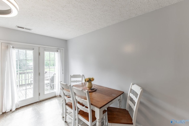 dining area featuring light floors, a textured ceiling, and visible vents