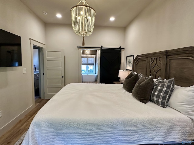 bedroom with a barn door, baseboards, wood finished floors, an inviting chandelier, and recessed lighting