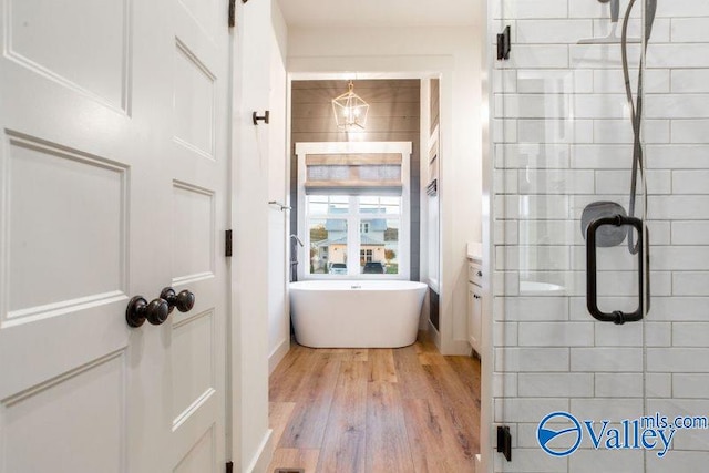 full bath featuring wood finished floors, a stall shower, and a freestanding tub