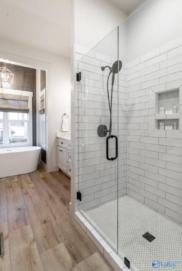 full bath with a freestanding tub, a shower stall, vanity, and wood finished floors