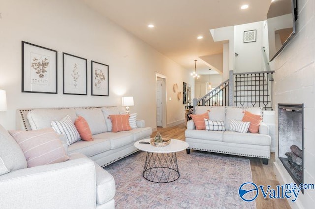 living area featuring a chandelier, stairway, wood finished floors, and recessed lighting